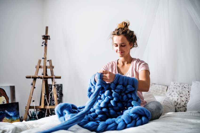 Frau beim arm knitting mit blauer Wolle